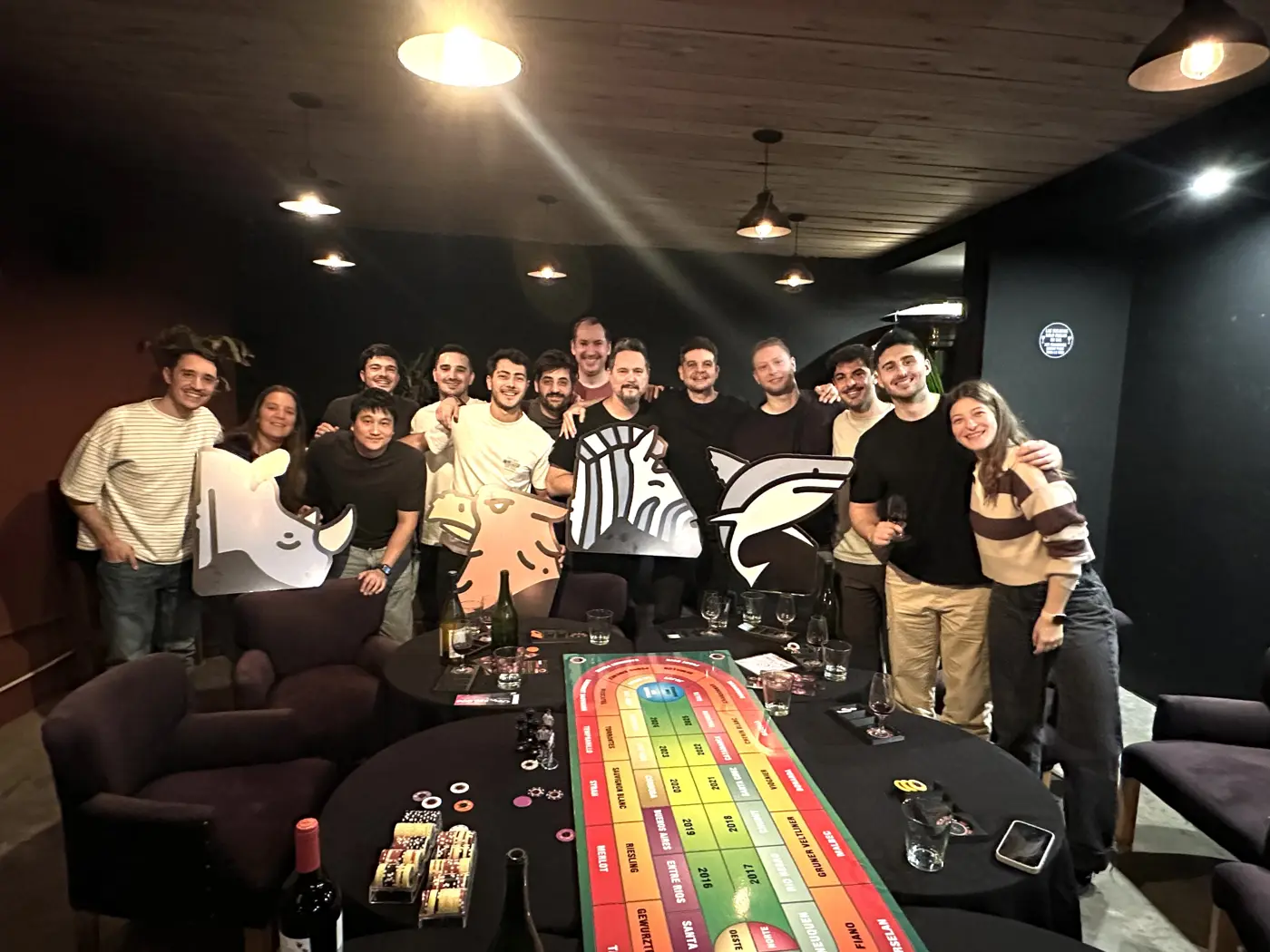 Equipo de trabajo posando con copas junto a la mesa de juego